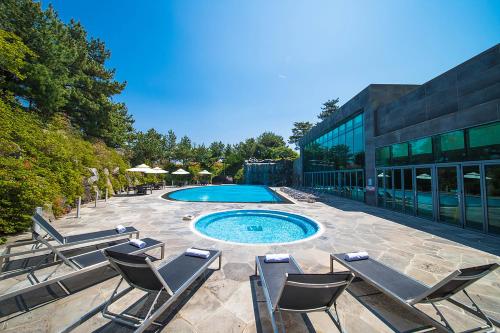 a patio with chairs and a pool in front of a building at WE Hotel Jeju in Seogwipo