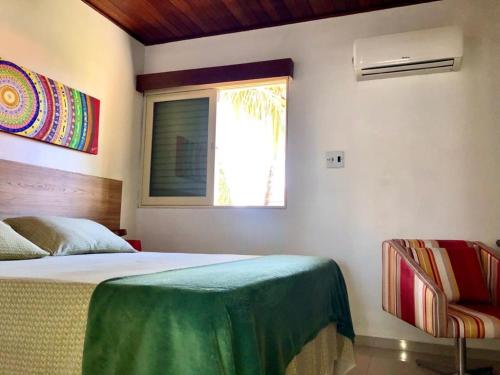 a bedroom with a bed and a window and a chair at Flat Cumaru ap 210 TEMPORADANOFRANCES Localização privilegiada e conforto in Praia do Frances