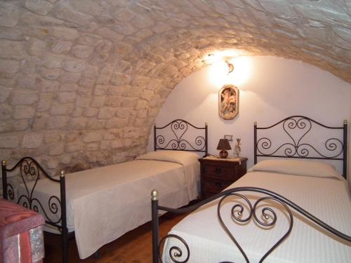 two beds in a room with a stone wall at Anticu Dammusu in Scicli