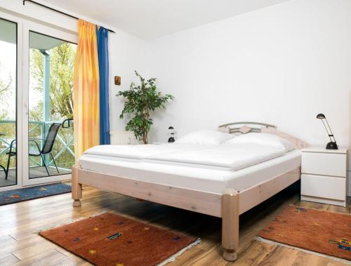 a bedroom with a bed and a balcony at Mann un Fru - Residenz am Yachthafen in Kirchdorf