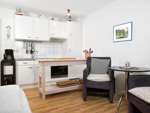 eine Küche mit weißen Schränken, einem Tisch und einem Stuhl in der Unterkunft Mann un Fru - Residenz am Yachthafen in Kirchdorf