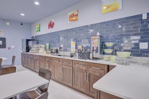 a kitchen with wooden cabinets and a blue tile wall at Quality Inn & Suites in Suffolk