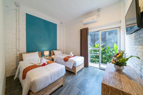 a bedroom with two beds and a large window at EUFORIA Guest House in Canggu