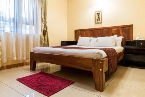 a bedroom with a wooden bed with a red rug at Great deal apartment - Blue Pearl in Kampala