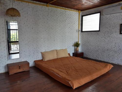 a bedroom with a large bed in a brick wall at ทุ่งยั้งเฮ้าส์ in Uttaradit