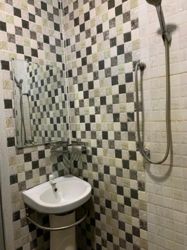 La salle de bains est pourvue d'un lavabo et d'une douche. dans l'établissement Aina Guest House, à Kota Bharu