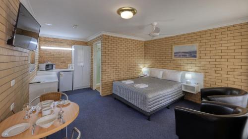 a hotel room with a bed and a table and a kitchen at Gunsynd Motor Inn in Goondiwindi