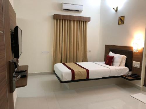 ein Hotelzimmer mit einem Bett und einem TV in der Unterkunft Hotel Grand Bee Bangalore in Bangalore