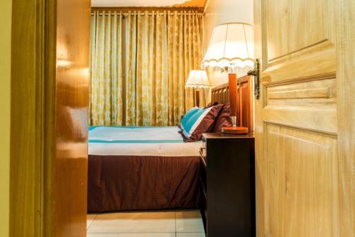 een slaapkamer met een bed met een lamp en een raam bij Apartment in secure Resort - 46 People in Kampala