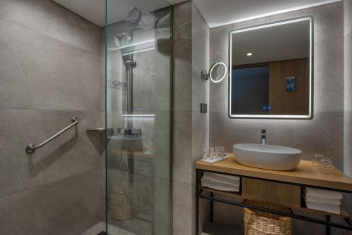 uma casa de banho com um lavatório e uma cabina de duche em vidro. em Park Inn by Radisson Shanghai Global Harbor em Xangai