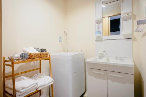 a small white bathroom with a sink and a refrigerator at 谷町君星ホテル九条27 in Osaka