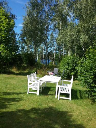 two white benches and a table in the grass at Björkslingan in Vimmerby