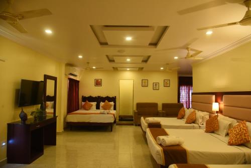 a hotel room with two beds and a couch at Hotel Ocean Heritage in Kanyakumari