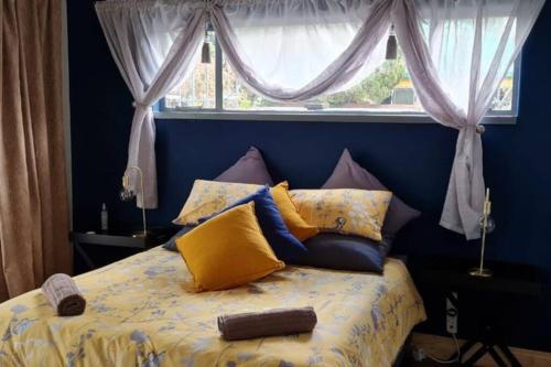 a bed with yellow and blue pillows and a window at Casa Bianco: Affordable luxury - Self Catering House in Parys