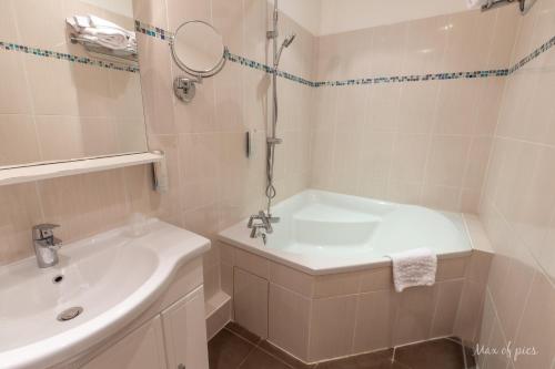 a bathroom with a sink and a tub and a mirror at Élysée Hôtel in Châteauroux