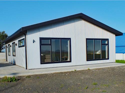 un pequeño edificio blanco con ventanas grandes en Skidbakki Guesthouse, 