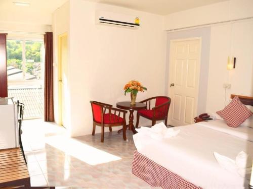Habitación con cama, mesa y sillas. en Hotel De Ratt en Phuket