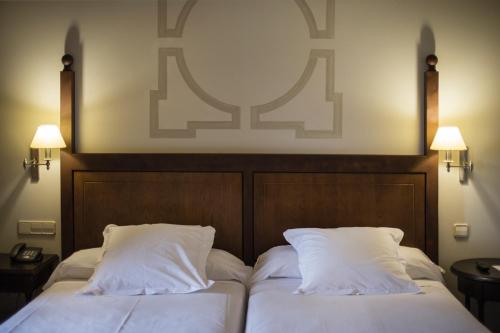 two beds in a hotel room with white pillows at Parador de Monforte de Lemos in Monforte de Lemos