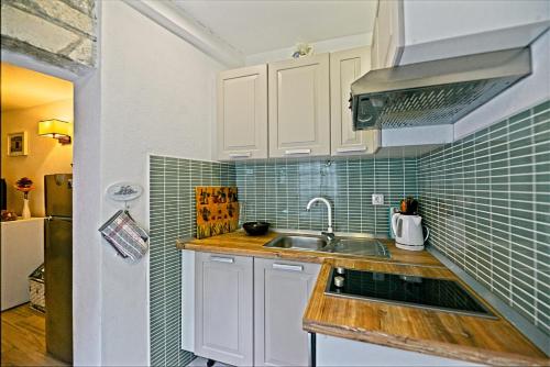 a kitchen with a sink and green tiles on the wall at "Ivanera" Postira otok Brač in Postira