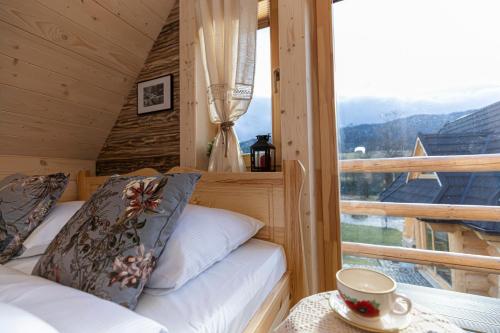 a room with two beds and a window with a cup on a table at TatryTop Osada Gazdówka z sauną in Kościelisko