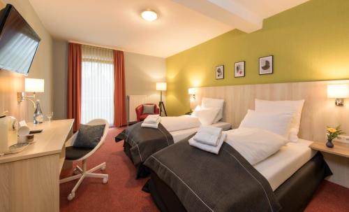 a hotel room with two beds and a desk at City Hotel Meckenheim in Meckenheim