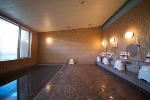 een badkamer met wastafels, spiegels en een bad bij Grand Hotel Hakusan in Hakusan