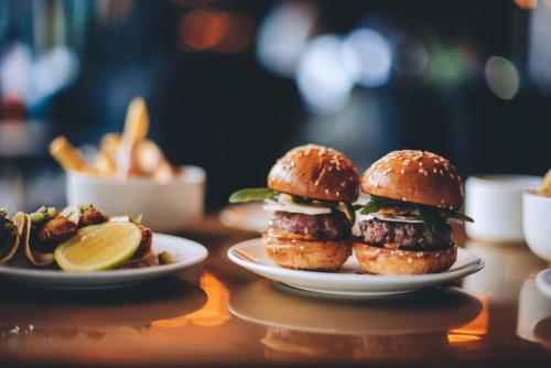 two plates of hamburgers on a table with food at The Alphen Boutique Hotel & Spa in Cape Town