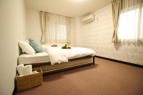 a bedroom with a bed with white sheets and a window at Okubo Hotel Hawaii in Tokyo