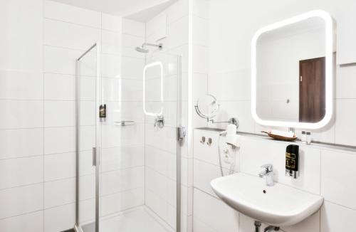 a white bathroom with a sink and a shower at Four Stars by City Hotel in Meckenheim