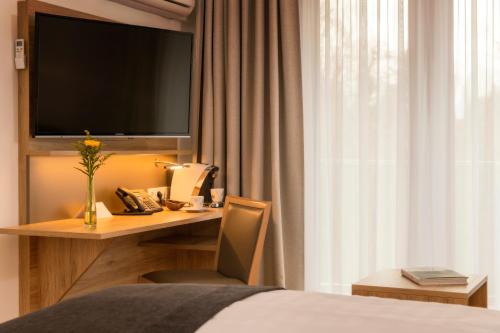 a hotel room with a desk with a television and a bed at Four Stars by City Hotel in Meckenheim