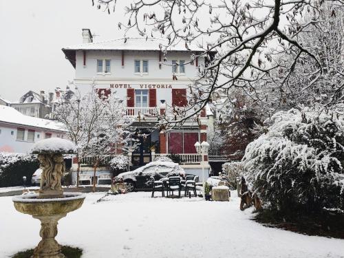 een sneeuwbedekte tuin met een gebouw en een fontein bij Studio dans Villa historique "Victoria" in Argelès-Gazost