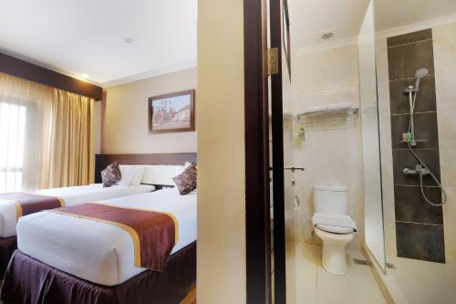 a hotel room with two beds and a shower at Royal Darmo Malioboro in Yogyakarta