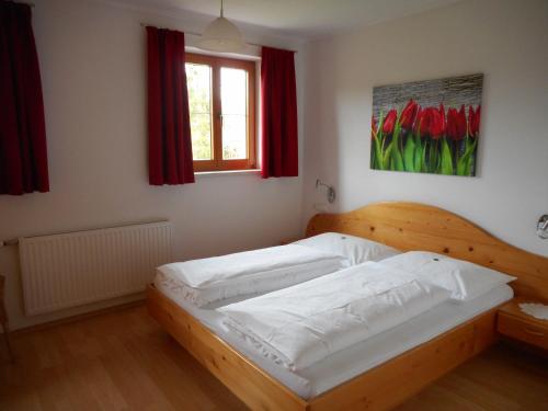 Rossleithen的住宿－欣德保爾霍夫里格爾農場假期酒店，一间设有木床的卧室,位于带红色窗帘的房间