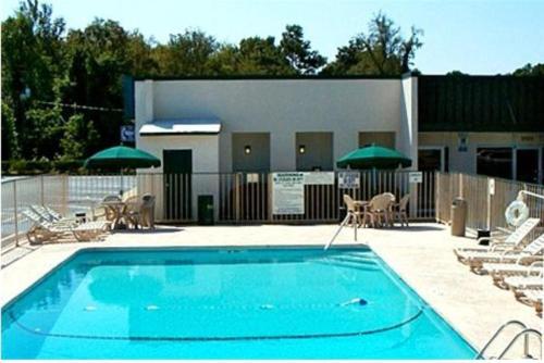 a swimming pool with chairs and umbrellas in front of a building at Masters Inn I-26 in Cayce