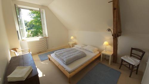 Un dormitorio con una cama y una ventana y una silla. en LA PINÇONNIERE, en Verneuil-sur-Indre