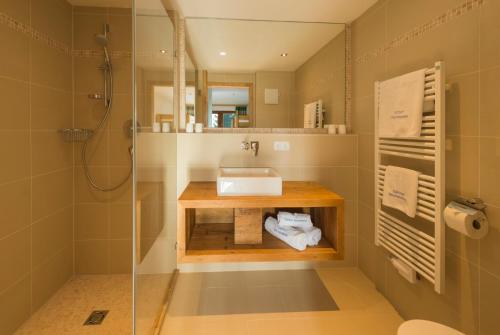 a bathroom with a sink and a glass shower at Lifesport Hotel Hechenmoos in Aurach bei Kitzbuhel