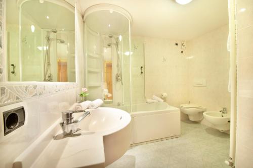 a white bathroom with a sink and a tub and a toilet at Appartamenti Duc De Rohan in Livigno
