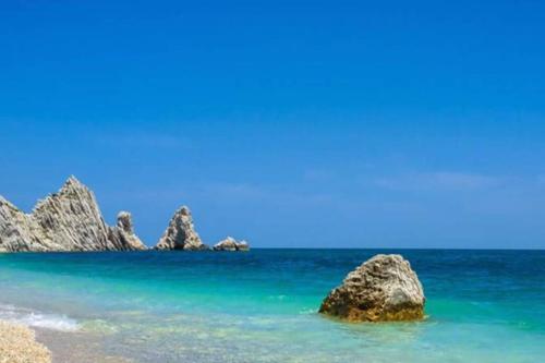 een uitzicht op het strand met rotsen in het water bij Mololocale in centro a Marcelli in Marcelli