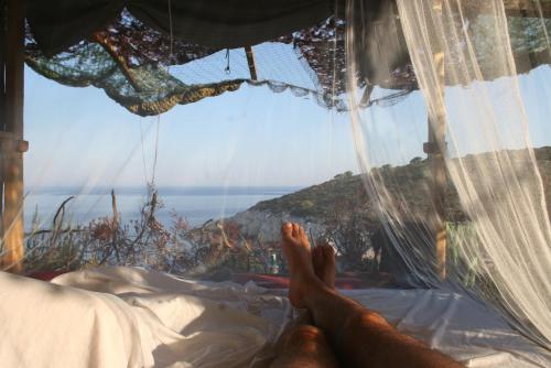 a person laying in a bed looking out at the ocean at islandescape-bisevo in Biševo