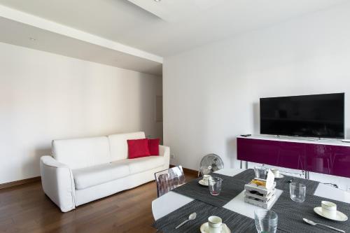 a living room with a white couch and a television at Roggia Apartments by Quokka 360 - central flats with parking space in Lugano