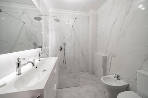 a white bathroom with a sink and a toilet at Casa Skyline by An Island Apart in Caniço