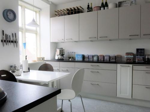 a kitchen with white cabinets and a table with chairs at ApartmentInCopenhagen Apartment 980 in Copenhagen