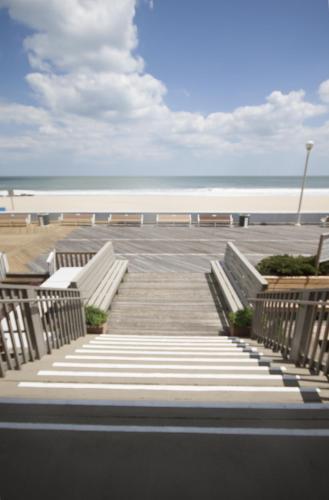 a group of benches on a beach with the ocean at Harrison Hall Hotel in Ocean City