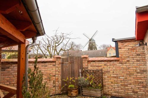 einen Steinzaun mit einer Windmühle im Hintergrund in der Unterkunft Ferienwohnungen Mühlenblick in Röbel