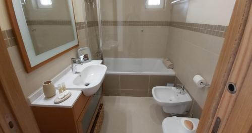 een badkamer met een wastafel, een toilet en een spiegel bij Paz em Resort de Luxo. in Cabanas de Tavira