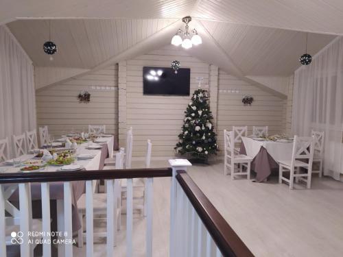 a dining room with a christmas tree and white tables and chairs at Pogar White in Slavske
