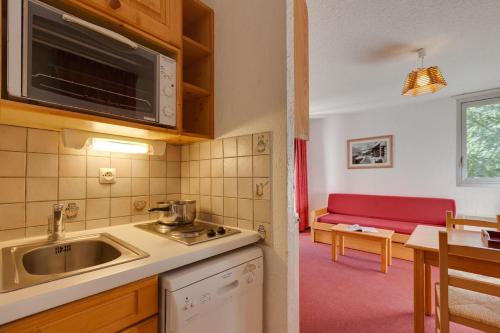 a kitchen with a sink and a red couch at Vacancéole - Résidence Côte Brune in Les Deux Alpes