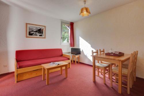 un salon avec un canapé rouge et une table dans l'établissement Vacancéole - Résidence Côte Brune, à Les Deux Alpes