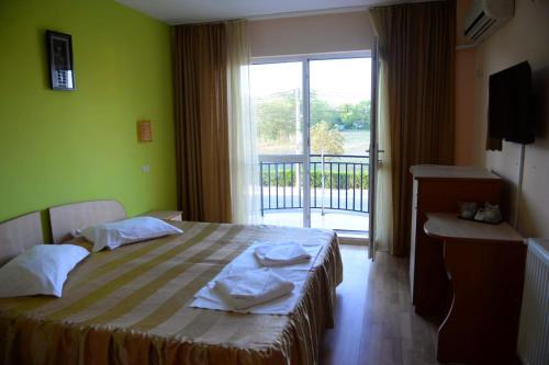Un dormitorio con una cama y una ventana con balcón. en Hotel Principal, en Costinesti