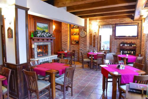 un restaurante con mesas y sillas y una chimenea en Family Hotel Lazur, en Bansko